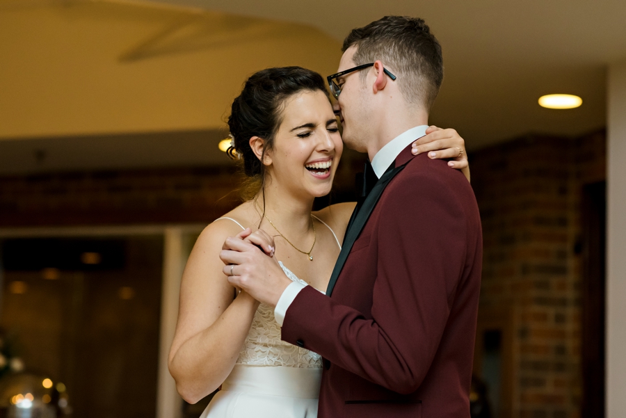 A bride laughing during her first dance with her new husband.